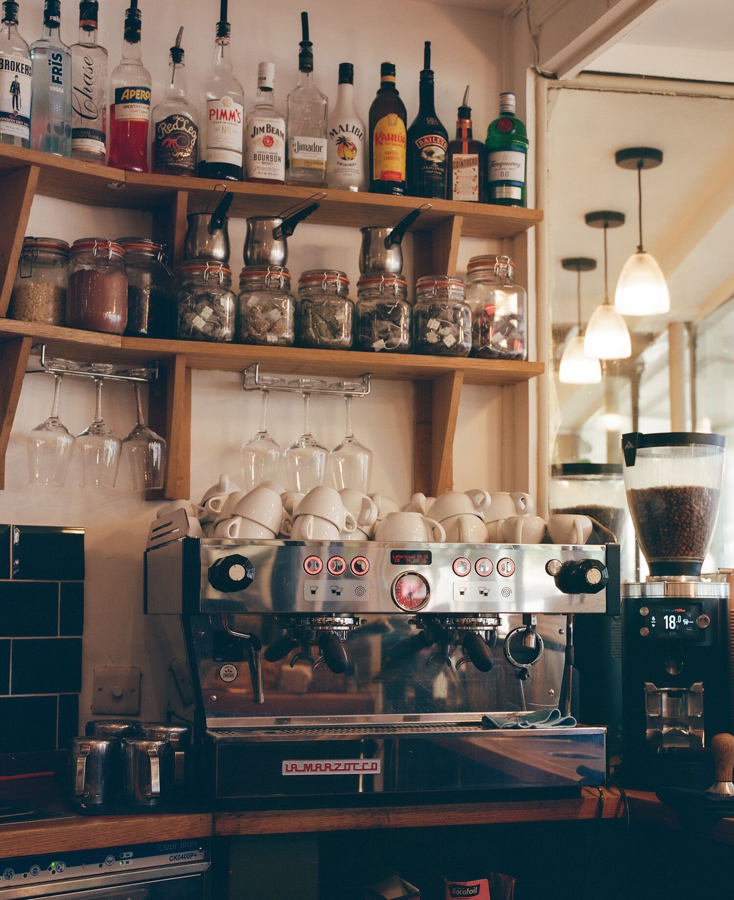 Odey's espresso machine beneath shelves of cups, coffee and spirits
